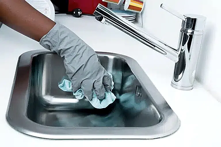 Woman cleaning a sink with gloves deep cleaning
